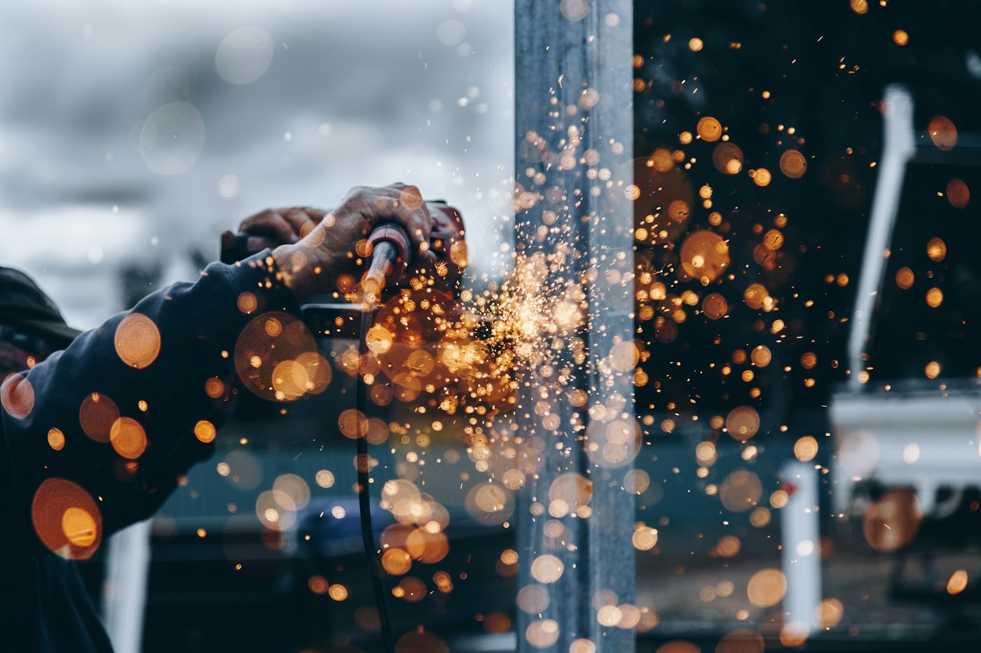A tradesperson at work, with warm sparks lighting the workshop